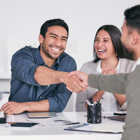 Man shaking hands while other employees smile