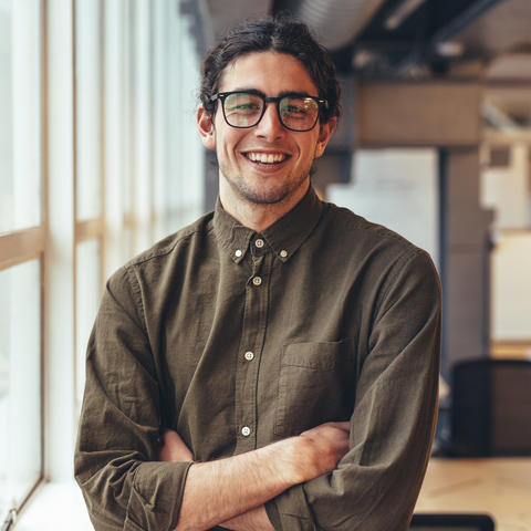Man standing with his arms folding smiling